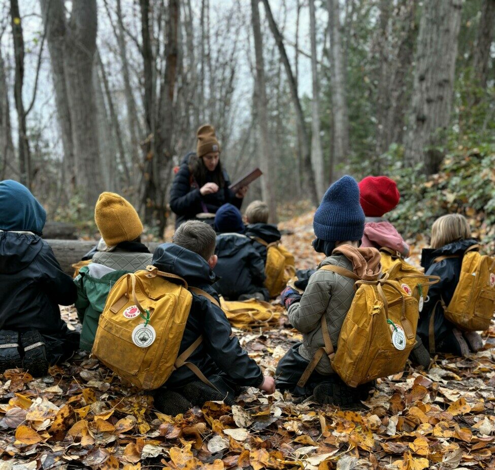 students sitting on ground in forest