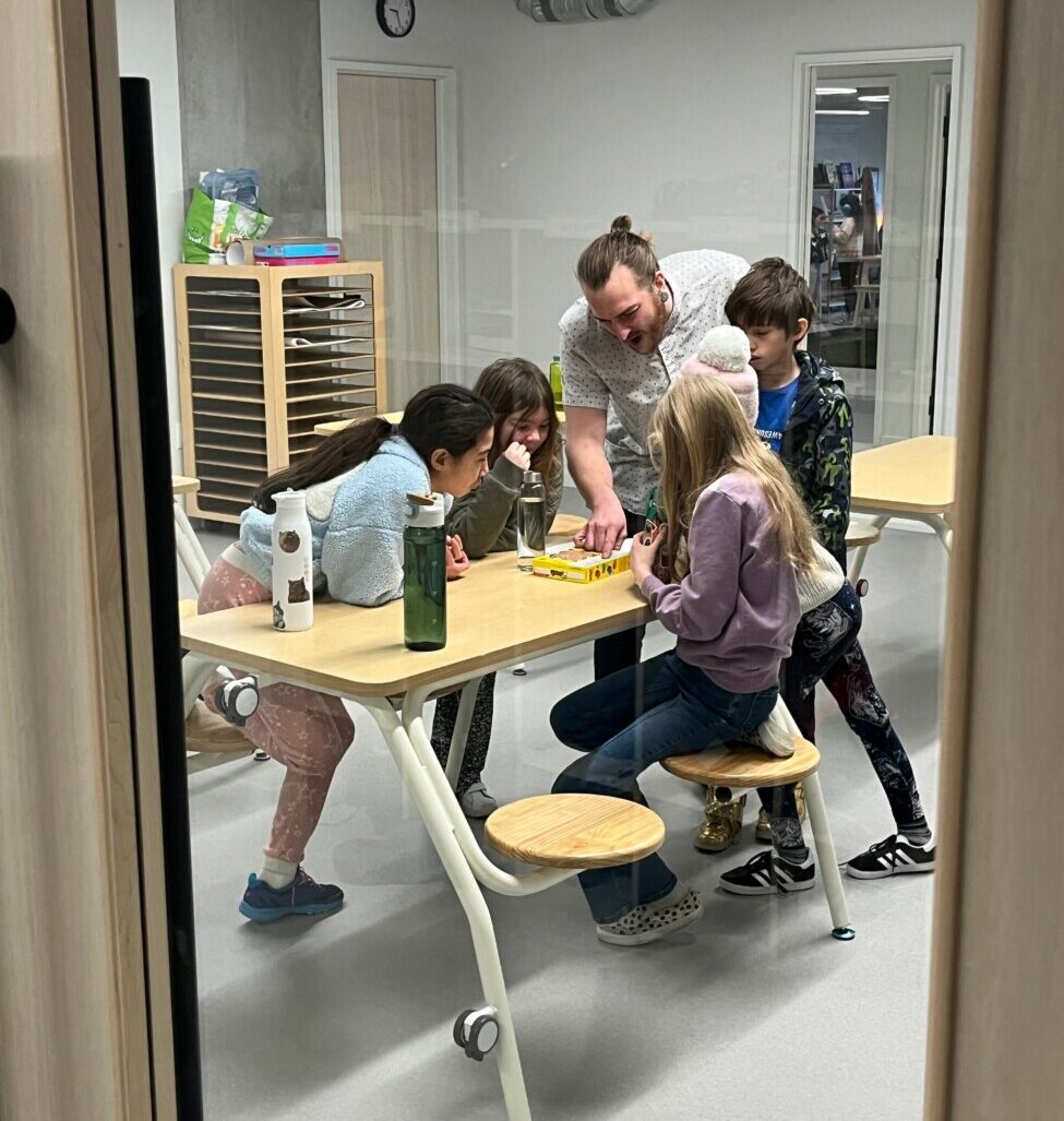 students surrounding desk with teacher